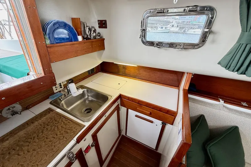 Slide: The Image of Cozy 1975 Soverel 37 yacht kitchen with sink, wooden cabinets, and nautical window view. - 16