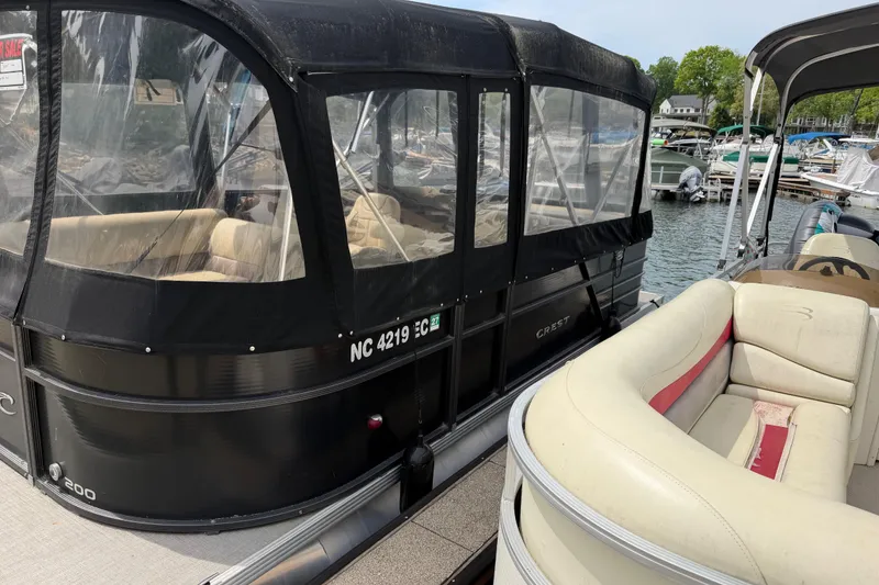 Slide: The Image of 2016 Crest I 200 L pontoon boat docked at marina with covered seating area. - 4