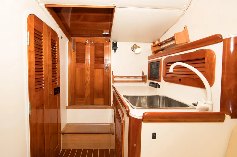 Slide: The Image of Interior of 1997 Hinckley Runabout 29, featuring wooden cabinetry and a compact sink area. - 10
