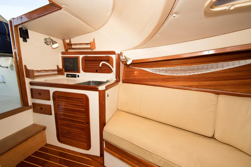 Slide: The Image of Interior of a 1997 Hinckley Runabout 29, featuring a cozy cabin with wooden accents. - 12