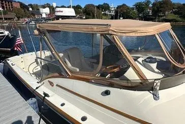 Slide: The Image of 1997 Hinckley Runabout 29 docked, featuring a tan canopy and classic design. - 15