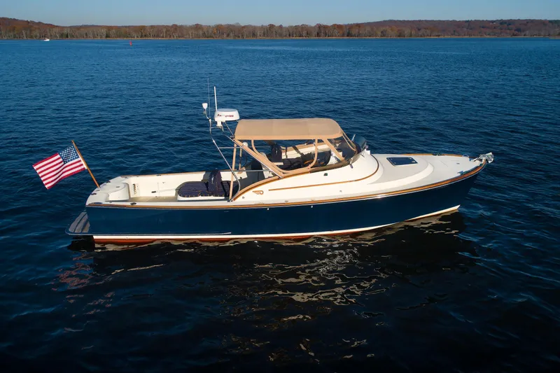 Slide: The Image of 1997 Hinckley Runabout 29 boat on calm water with American flag. - 16