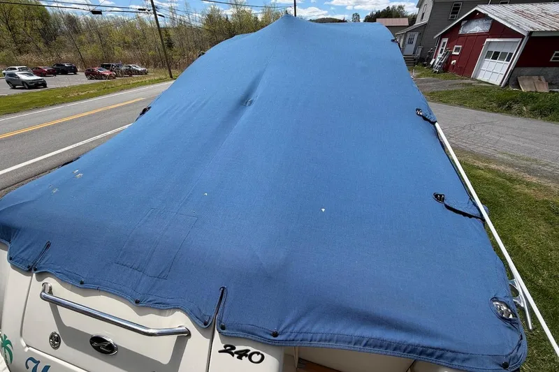 Slide: The Image of Covered 2002 Sea Ray 240 Sundancer boat parked near a road and buildings. - 13