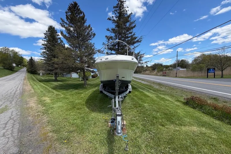Slide: The Image of 2002 Sea Ray 240 Sundancer boat on trailer beside a rural road, under a blue sky. - 2