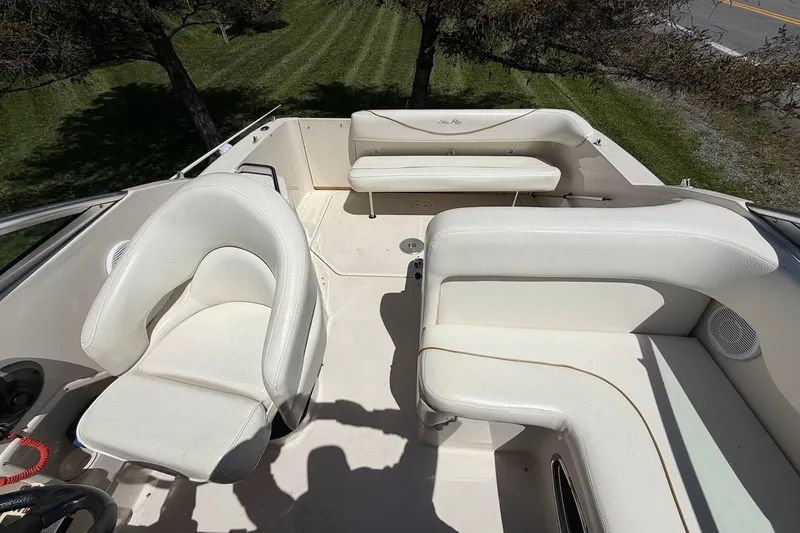 Slide: The Image of 2002 Sea Ray 240 Sundancer boat interior with white seating and steering area. - 21