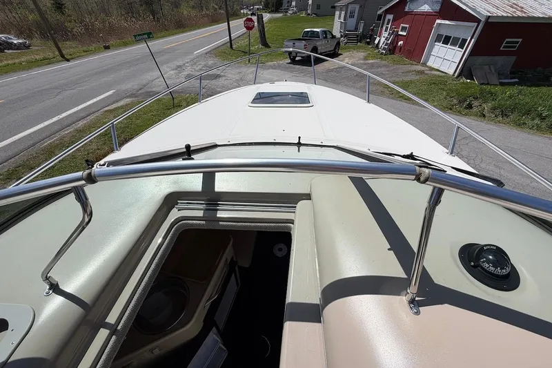Slide: The Image of 2002 Sea Ray 240 Sundancer boat parked near a rural road and buildings. - 23