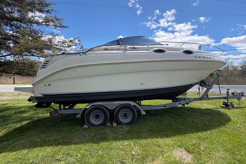 Slide: The Image of 2002 Sea Ray 240 Sundancer boat on trailer, parked on grass under blue sky. - 3
