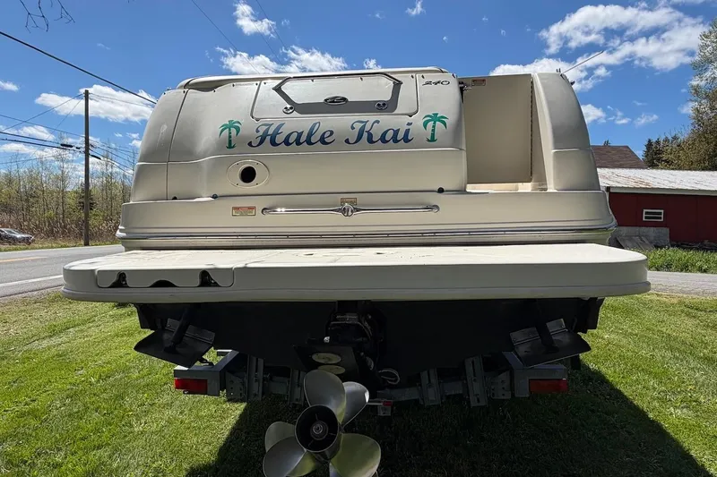 Slide: The Image of 2002 Sea Ray 240 Sundancer boat on grass, rear view with "Hale Kai" text. - 4