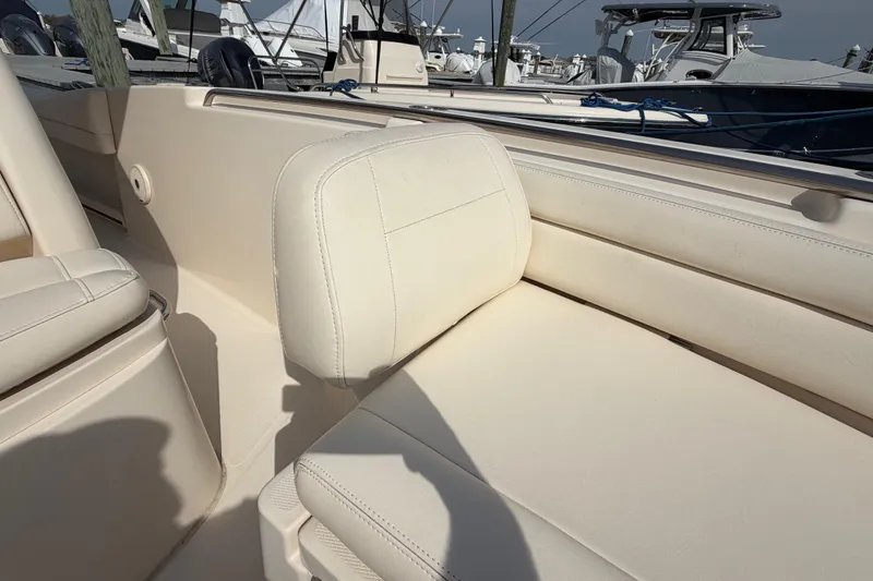 Slide: The Image of 2018 Grady-White Fisherman 236 boat interior with beige seating at a marina. - 13