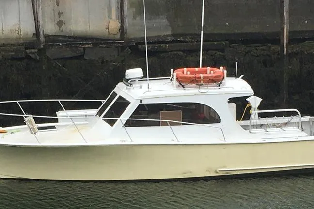 The Image of 1996 KenCraft Down East Express 35 boat docked, featuring a white hull and orange lifebuoy. - 0