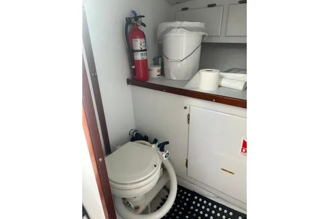 Slide: The Image of 1996 KenCraft Down East Express 35 boat bathroom with toilet, fire extinguisher, and storage cabinets. - 17