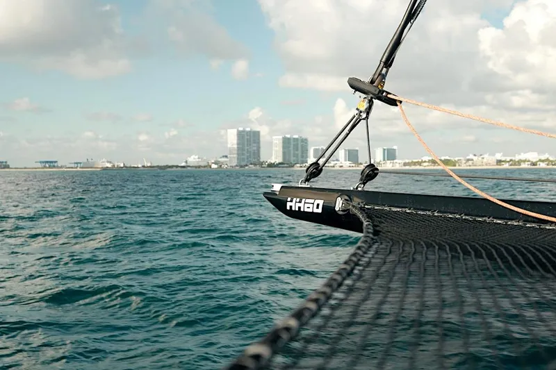 Slide: The Image of 2026 HH Catamarans HH60 sailing near a coastal city skyline under a partly cloudy sky. - 11