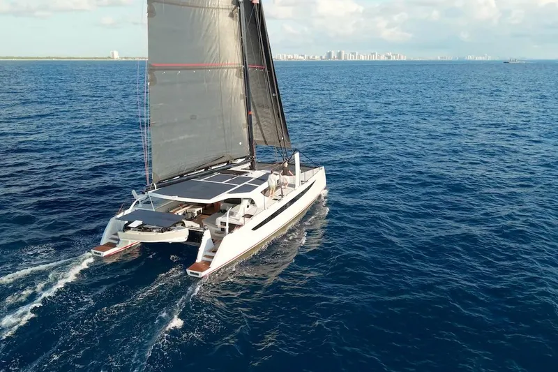 Slide: The Image of 2026 HH Catamarans HH60 sailing on open ocean with city skyline in background. - 3