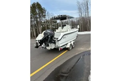 Slide: The Image of 1999 Boston Whaler 21 Outrage boat on trailer, parked on a road near trees. - 2