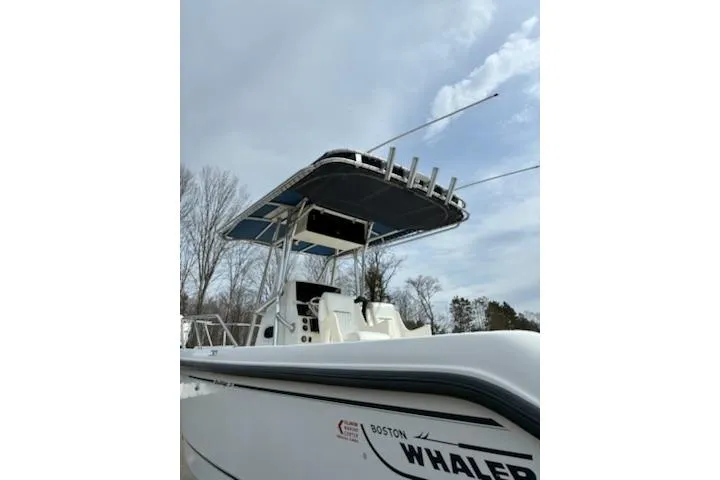 Slide: The Image of 1999 Boston Whaler 21 Outrage boat with T-top and rod holders under a cloudy sky. - 4