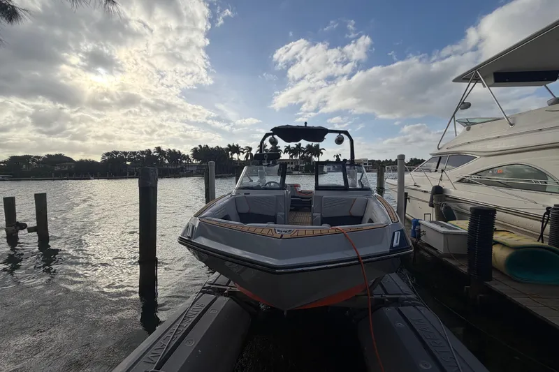 Slide: The Image of 2022 Nautique Super Air Nautique G25 boat docked on a sunny waterfront. - 2