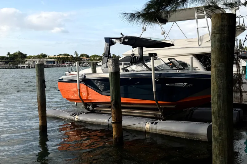 Slide: The Image of 2022 Nautique Super Air Nautique G25 boat docked on a sunny day with palm trees. - 3