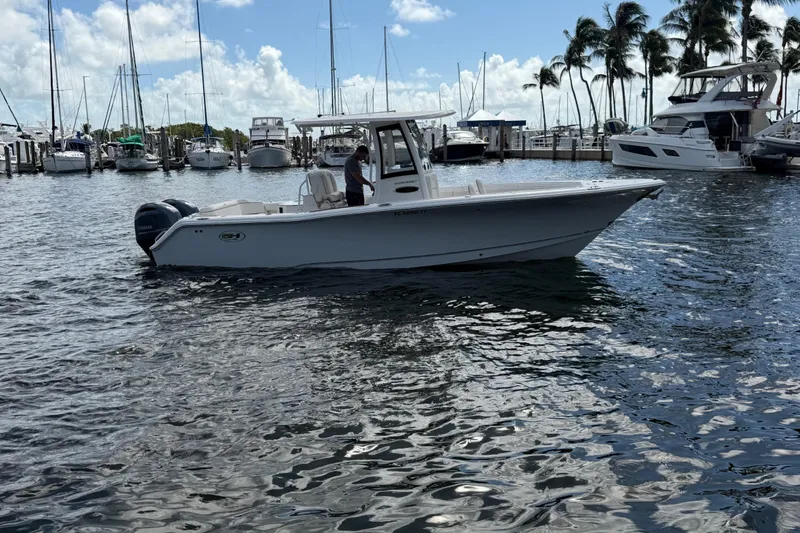 Slide: The Image of 2022 Sea Hunt Ultra 275 SE boat docked in a marina with palm trees. - 11