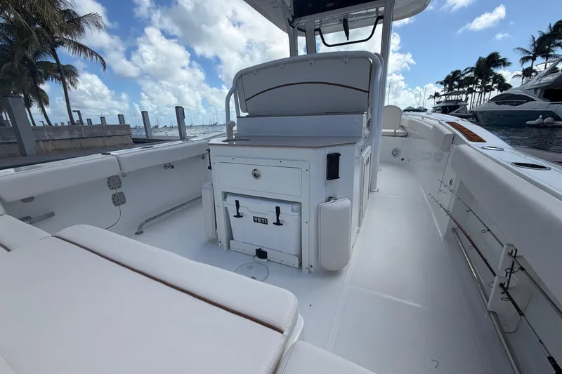 Slide: The Image of 2022 Sea Hunt Ultra 275 SE boat interior with seating and storage, docked by palm trees. - 18
