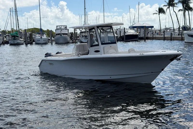 Slide: The Image of 2022 Sea Hunt Ultra 275 SE boat docked in a marina with sailboats and palm trees. - 3