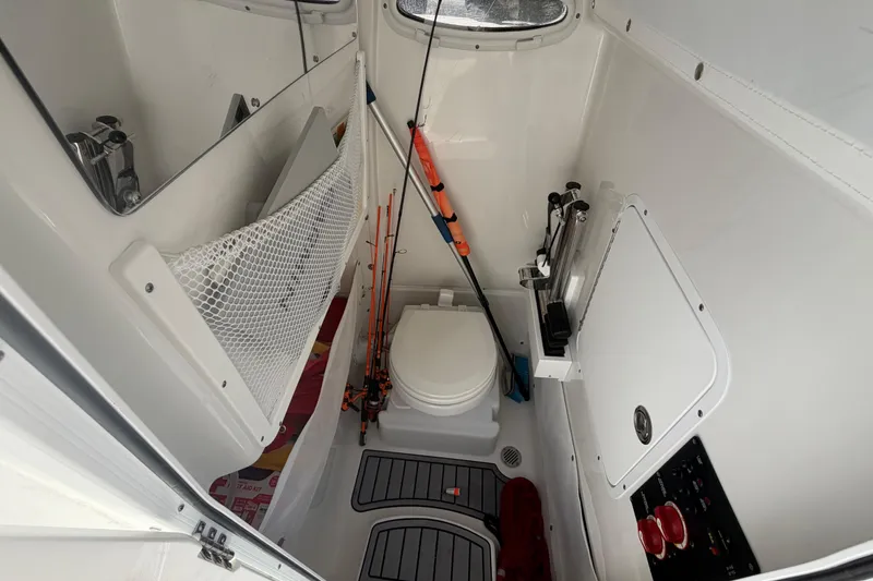 Slide: The Image of Interior of 2022 Sea Hunt Ultra 275 SE boat, featuring a compact bathroom with fishing gear. - 34