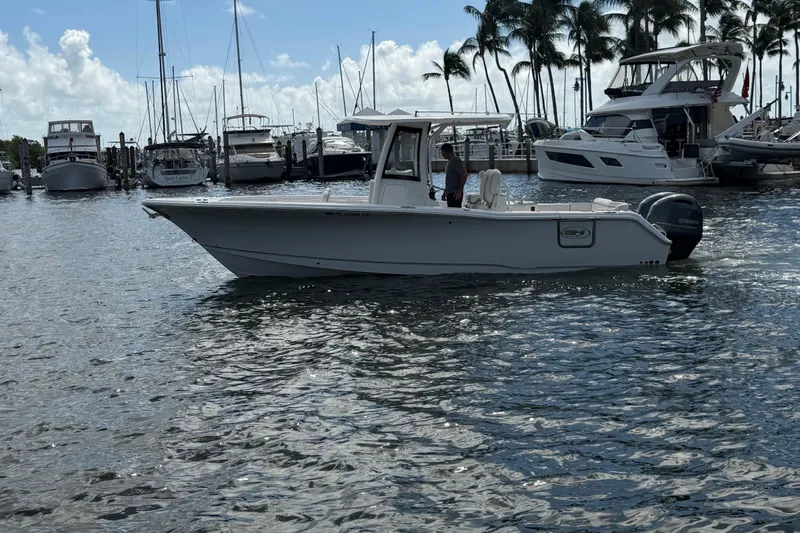 Slide: The Image of 2022 Sea Hunt Ultra 275 SE boat docked in a marina with palm trees. - 4