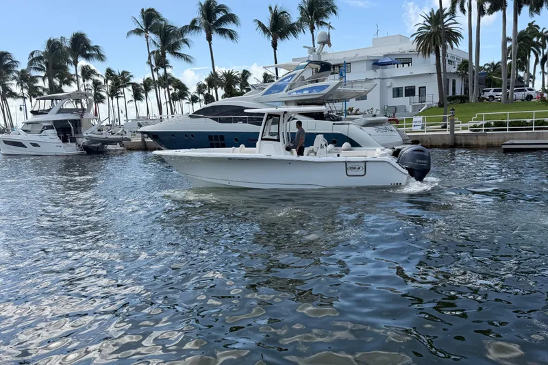 Slide: The Image of 2022 Sea Hunt Ultra 275 SE boat cruising in a marina with palm trees and yachts. - 5