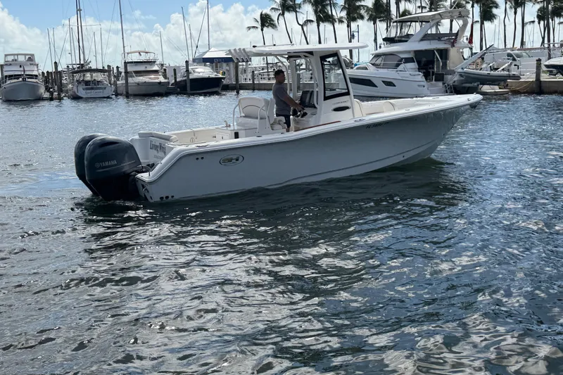 Slide: The Image of 2022 Sea Hunt Ultra 275 SE boat on water near marina with palm trees. - 9