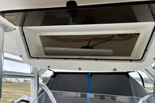 Slide: The Image of 2015 Edgewater 245CC boat interior, featuring a storage compartment and visible wiring. - 16