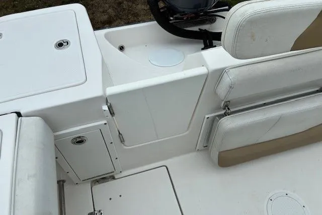 Slide: The Image of 2015 Edgewater 245CC boat interior with white seating and storage compartments. - 18