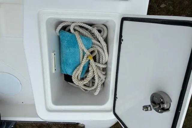 Slide: The Image of Storage compartment on 2015 Edgewater 245CC boat with rope and towel inside. - 20