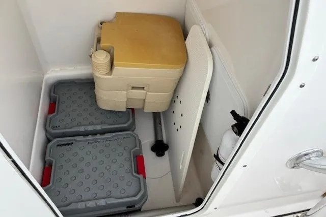 Slide: The Image of Storage compartment in a 2015 Edgewater 245CC boat with portable toilet and gear boxes. - 23