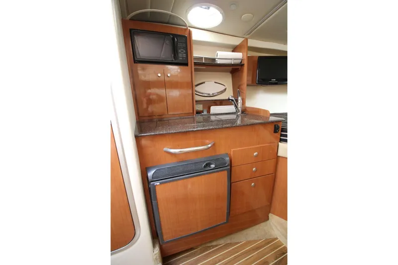 Slide: The Image of 2008 Maxum 2900 SE boat interior kitchen with microwave, sink, and wooden cabinetry. - 28