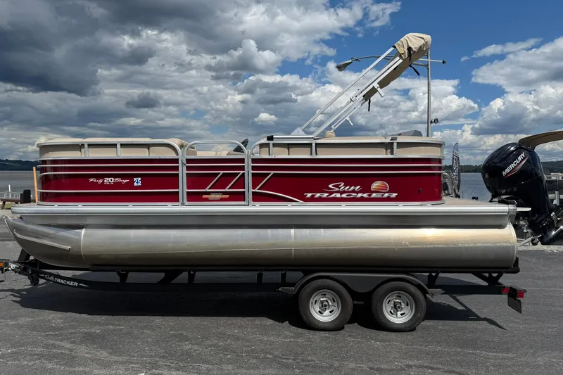 The Image of 2023 Sun Tracker Party Barge 20 DLX pontoon boat on trailer, under cloudy sky. - 1