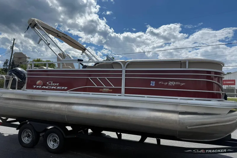 Slide: The Image of 2023 Sun Tracker Party Barge 20 DLX pontoon boat on trailer under cloudy sky. - 6