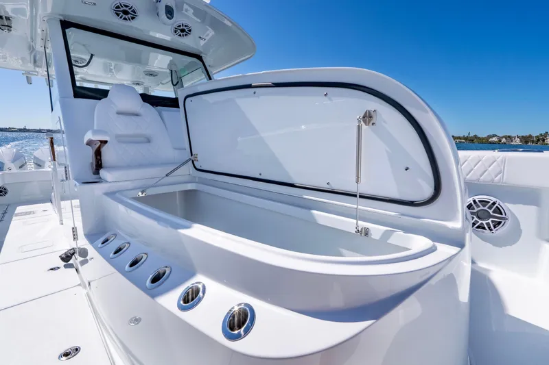 Slide: The Image of 2026 Freeman 35 boat with open storage compartment, luxurious seating, and ocean backdrop. - 24