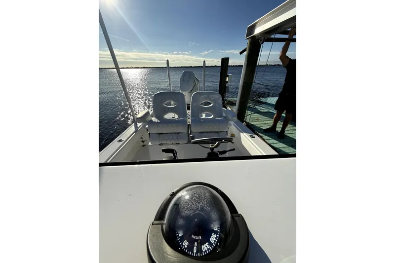 Slide: The Image of 2024 Contender 25 Bay boat interior with dual seats and compass, docked by the water. - 12