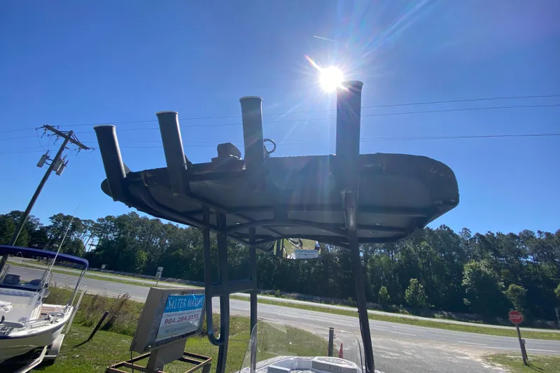 Slide: The Image of 2023 Yamaha Boats 195 FSH Sport under bright sun, showcasing T-top structure. - 9