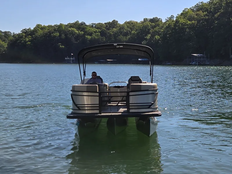 Slide: The Image of A 2026 Starcraft EXS 1 R pontoon boat on a calm lake with a wooded shoreline. - 35