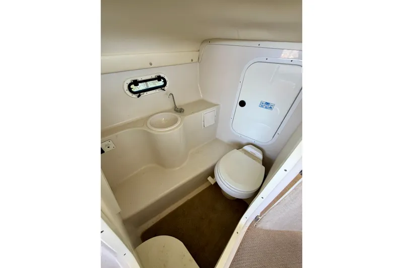 Slide: The Image of 2004 Four Winns 280 Horizon boat bathroom with sink, toilet, and porthole window. - 23