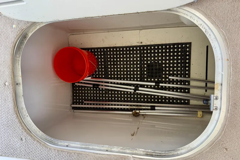 Slide: The Image of Storage compartment of 2004 Four Winns 280 Horizon boat with red bucket and metal poles. - 25