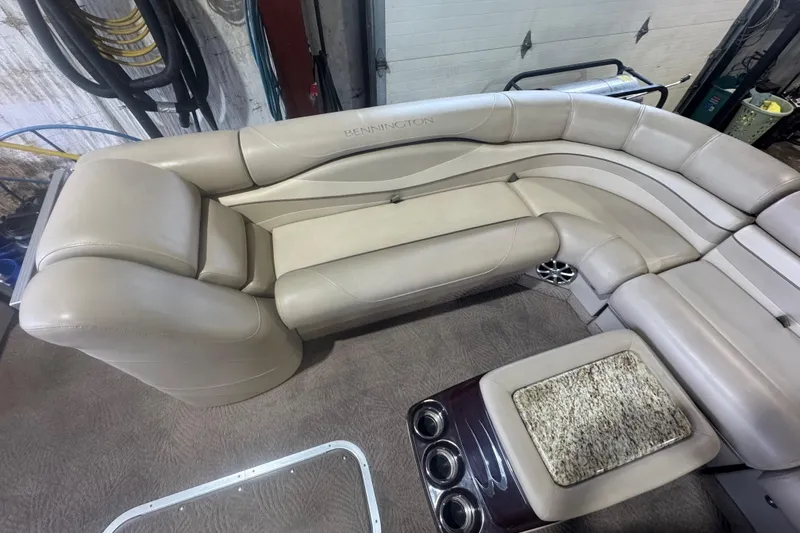 Slide: The Image of Luxurious seating on a 2010 Bennington 2550RCW boat, featuring beige upholstery and cup holders. - 11