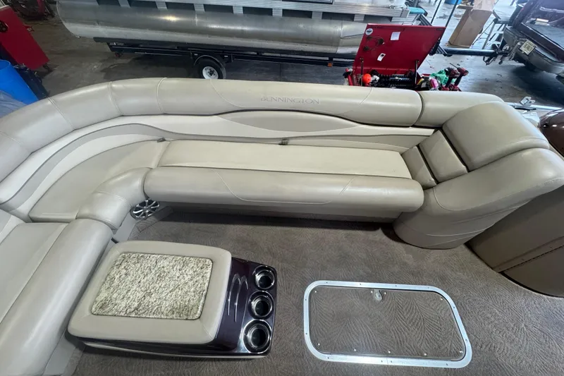 Slide: The Image of 2010 Bennington 2550RCW boat interior with beige seating and cup holders. - 12
