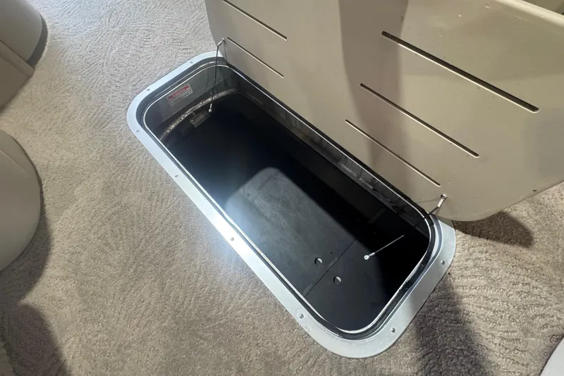 Slide: The Image of Open storage compartment on 2010 Bennington 2550RCW boat, featuring carpeted flooring. - 14
