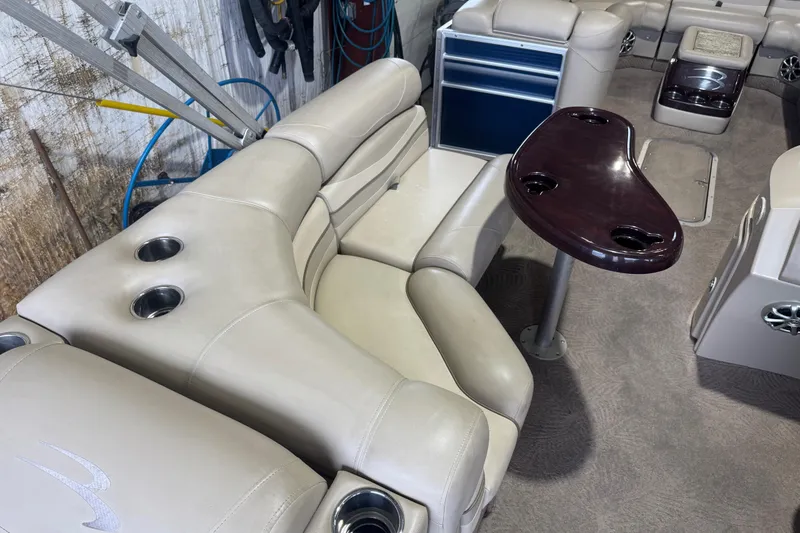 Slide: The Image of Interior of a 2010 Bennington 2550RCW boat with beige seating and a wooden table. - 20