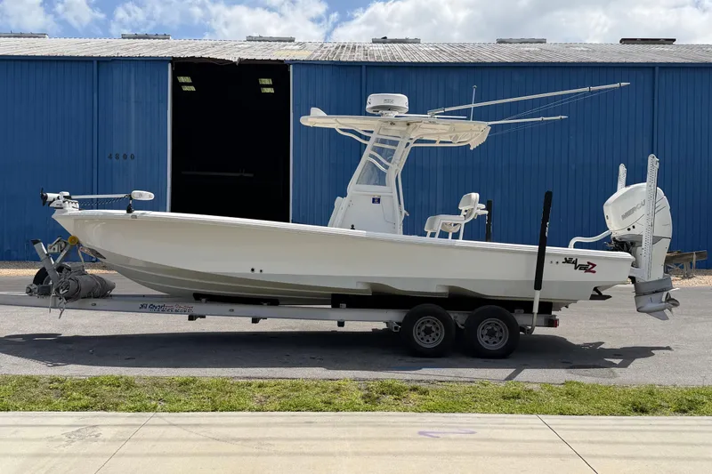 Slide: The Image of 2019 Sea Vee 270Z boat on trailer, parked near blue warehouse. - 2