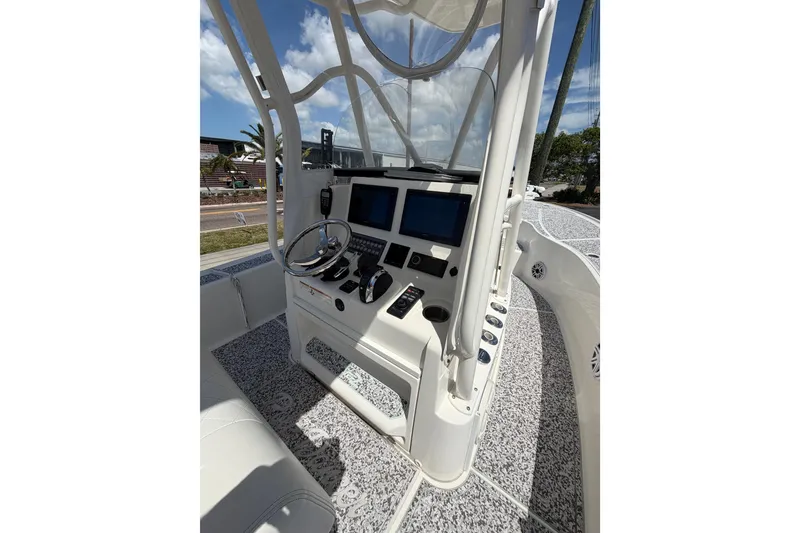 Slide: The Image of 2019 Sea Vee 270Z boat console with steering wheel and navigation screens under clear sky. - 20
