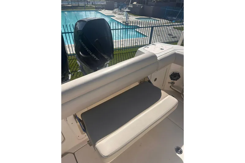Slide: The Image of 2023 Boston Whaler 280 Outrage boat interior with Mercury engine by a pool. - 16