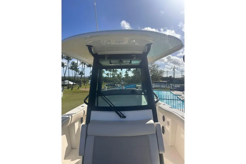 Slide: The Image of 2023 Boston Whaler 280 Outrage boat helm with windshield and seating, sunny outdoor setting. - 17