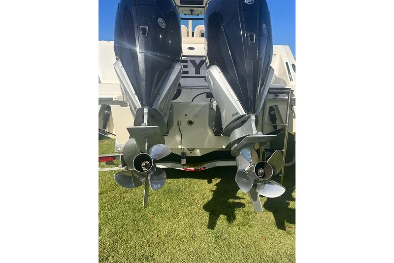 Slide: The Image of Twin outboard engines on a 2023 Boston Whaler 280 Outrage boat, displayed on grass. - 3